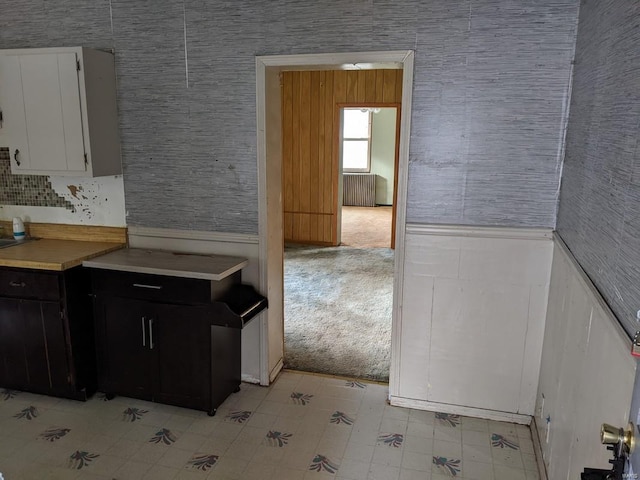 kitchen featuring white cabinets, light colored carpet, and radiator