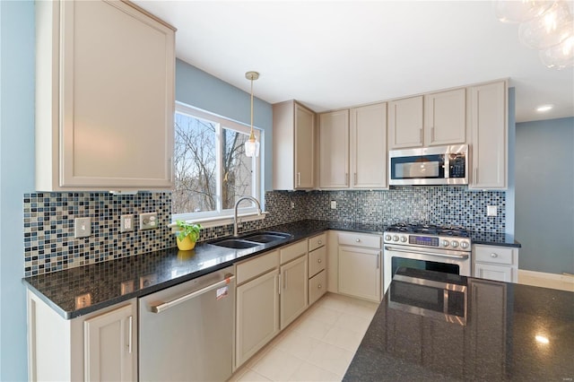 kitchen featuring sink, hanging light fixtures, backsplash, dark stone countertops, and appliances with stainless steel finishes