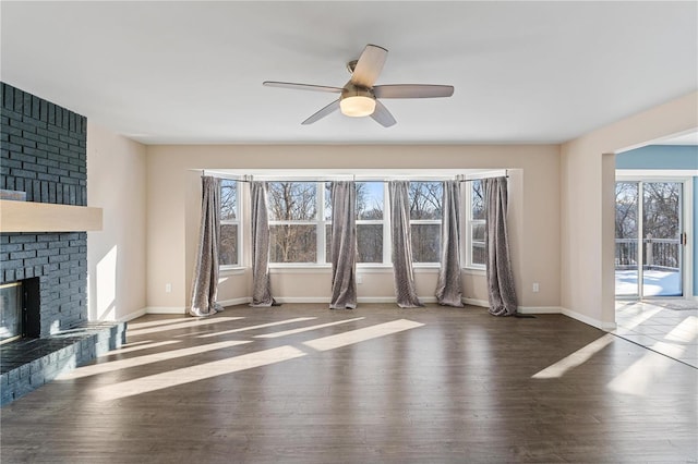 unfurnished living room with a fireplace, dark hardwood / wood-style flooring, and ceiling fan