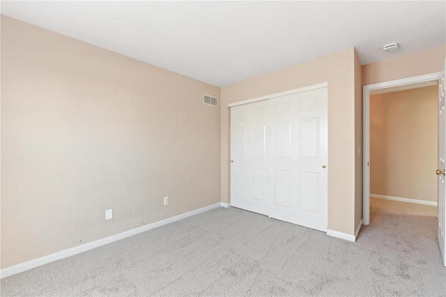 unfurnished bedroom with light carpet and a closet