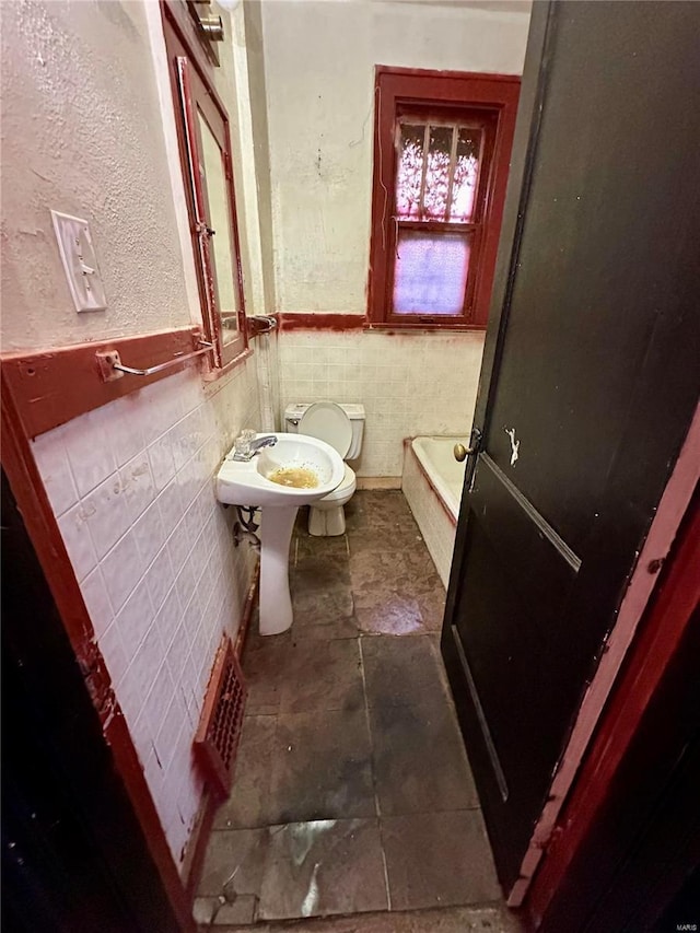 bathroom featuring toilet, tile walls, and a tub