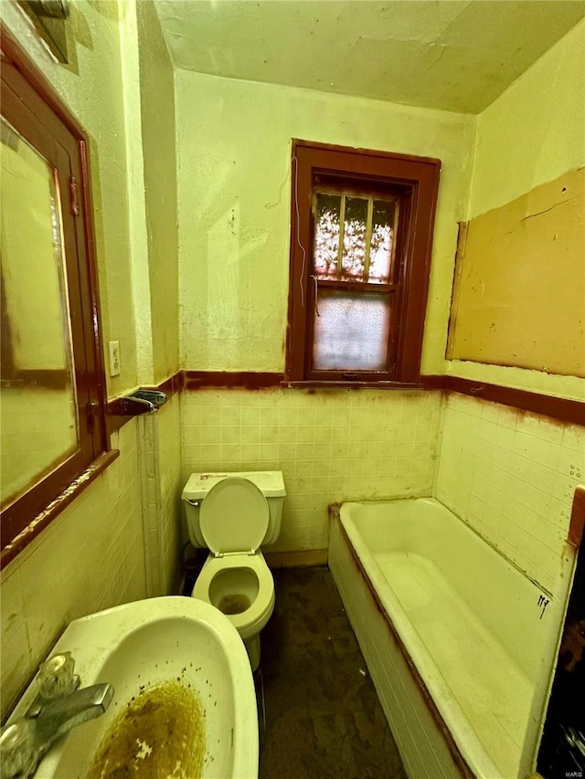 bathroom featuring toilet, a bathtub, tile walls, and sink