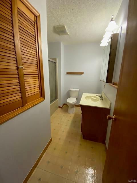 bathroom with vanity, an enclosed shower, a textured ceiling, and toilet