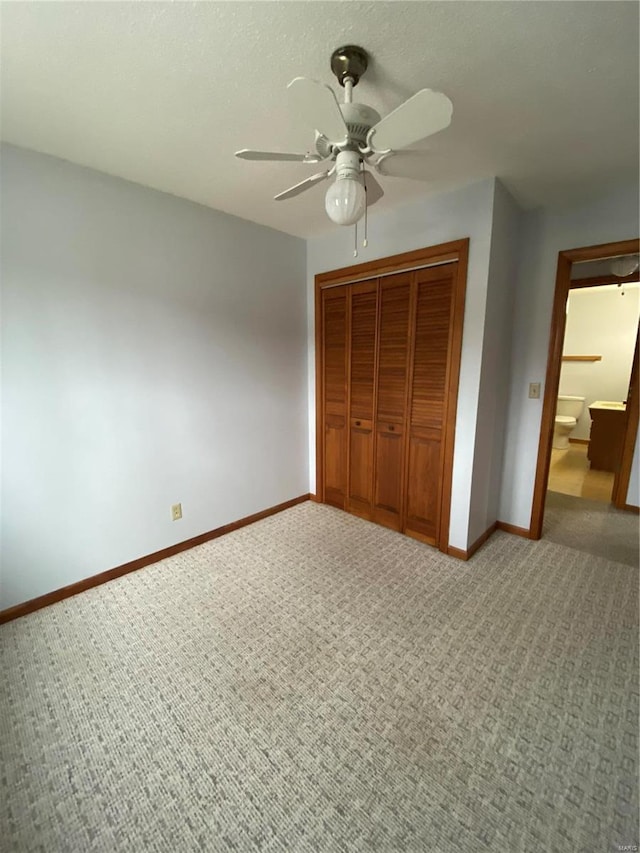 unfurnished bedroom featuring carpet, ceiling fan, ensuite bath, and a closet