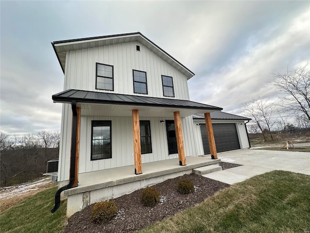 modern farmhouse featuring a garage, covered porch, central air condition unit, and a front lawn