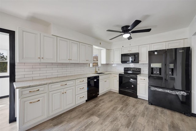 kitchen with sink, light hardwood / wood-style flooring, backsplash, white cabinets, and black appliances