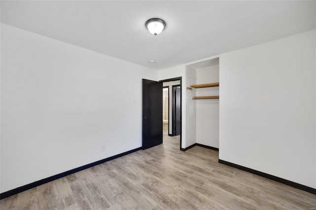 unfurnished bedroom with a spacious closet, light hardwood / wood-style flooring, and a closet