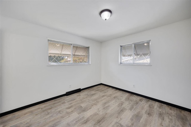 spare room featuring a wealth of natural light and light hardwood / wood-style floors