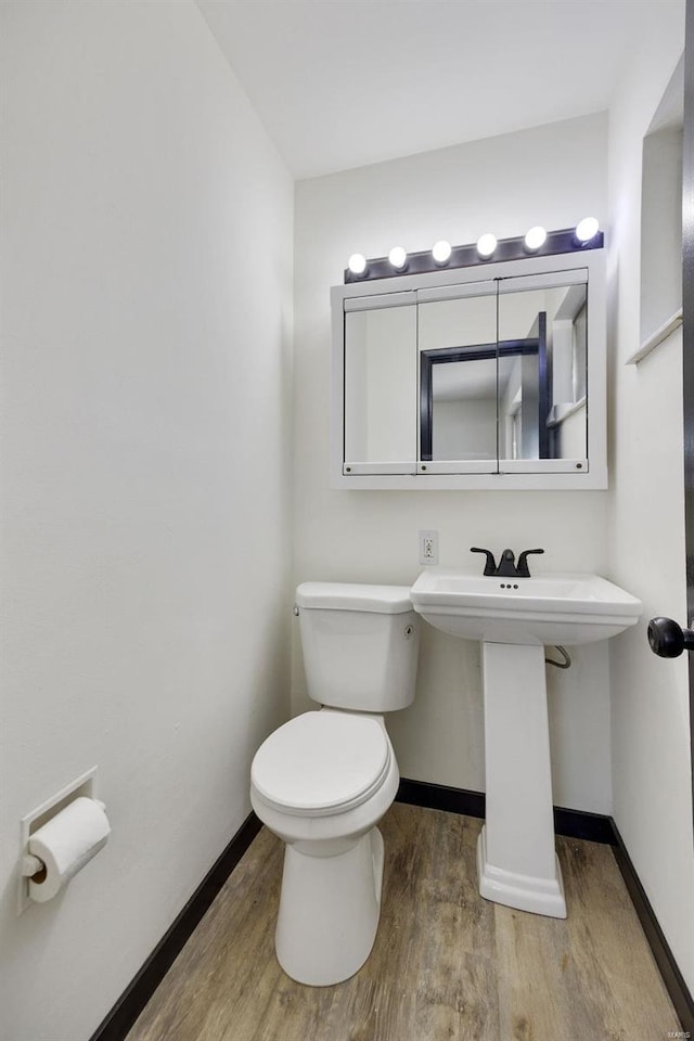 bathroom with toilet, wood-type flooring, and sink