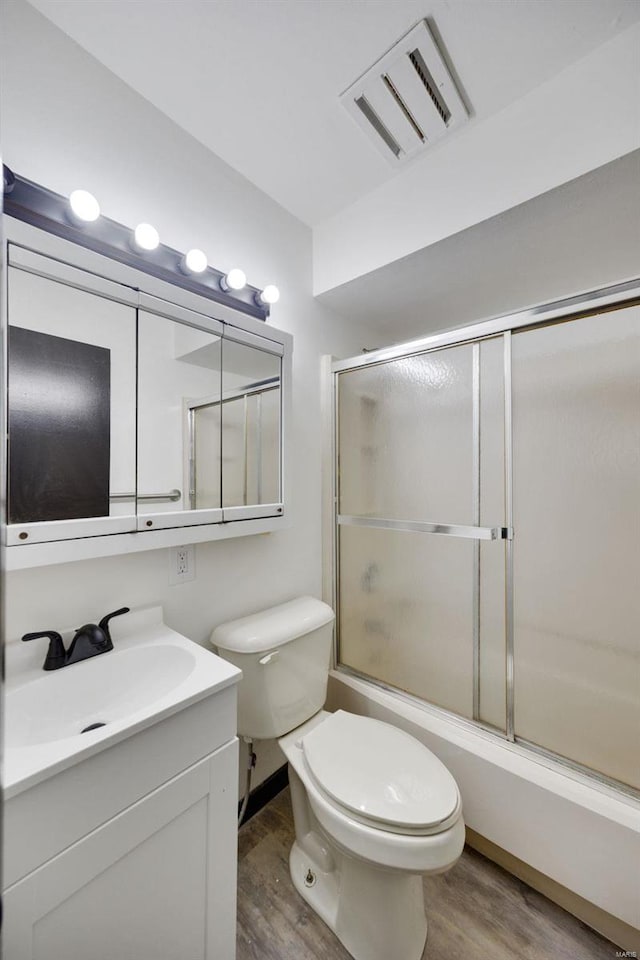 full bathroom featuring enclosed tub / shower combo, vanity, wood-type flooring, and toilet