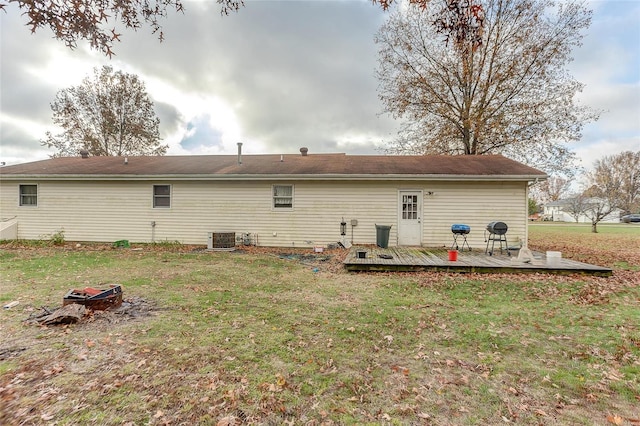 back of house with a yard, a wooden deck, and central AC