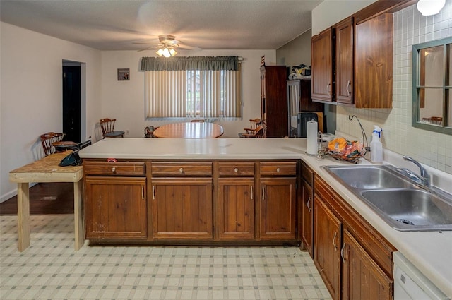 kitchen featuring dishwasher, sink, ceiling fan, tasteful backsplash, and kitchen peninsula