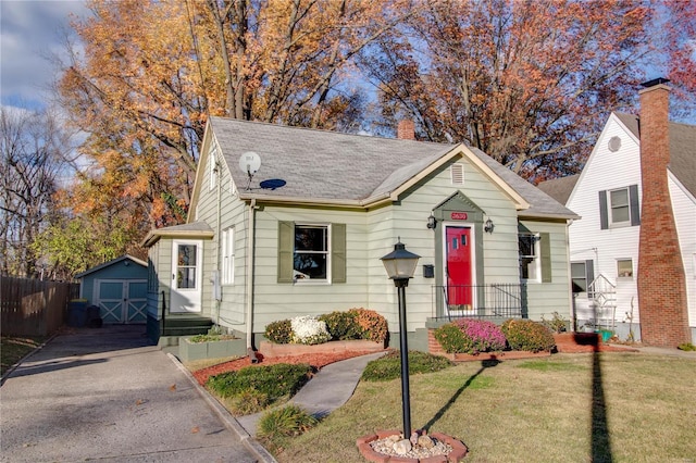 bungalow-style house featuring a front yard and a storage shed