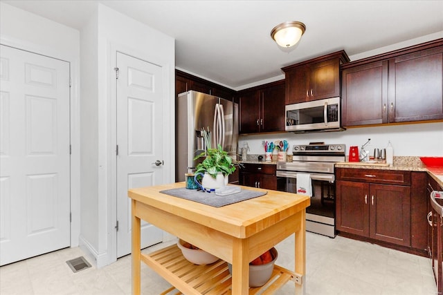 kitchen featuring light stone countertops, dark brown cabinets, and appliances with stainless steel finishes