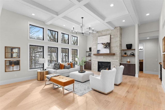 living room featuring beamed ceiling, a stone fireplace, a chandelier, and light hardwood / wood-style floors