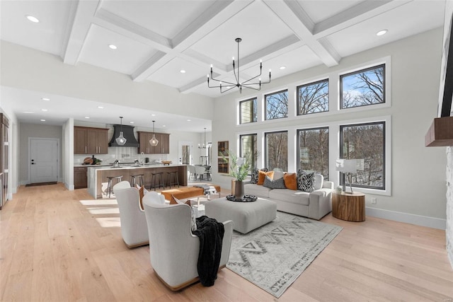 living room featuring beam ceiling, coffered ceiling, light wood-type flooring, and an inviting chandelier