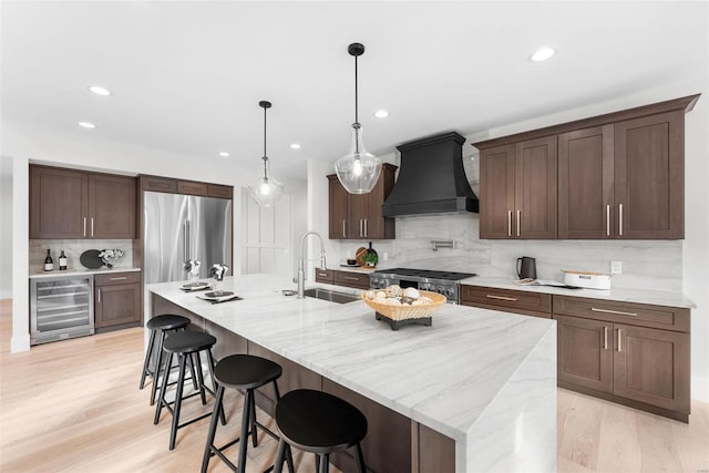 kitchen featuring sink, beverage cooler, backsplash, custom exhaust hood, and stainless steel appliances