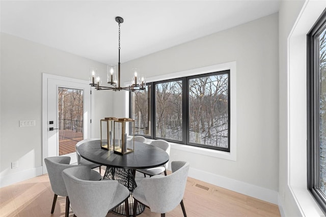 dining space with an inviting chandelier, plenty of natural light, and light hardwood / wood-style flooring