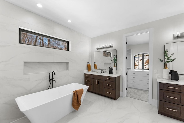 bathroom with vanity, a tub to relax in, and tile walls