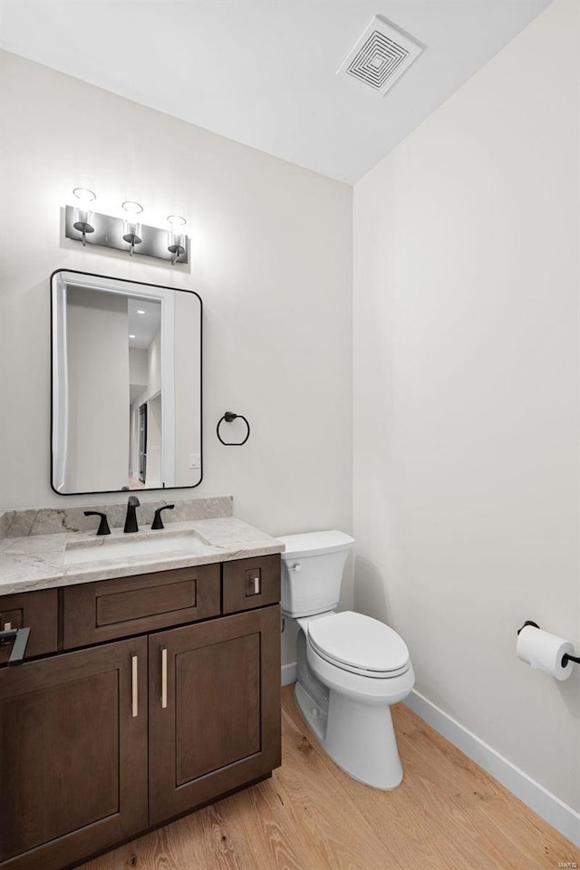 bathroom featuring vanity, hardwood / wood-style flooring, and toilet