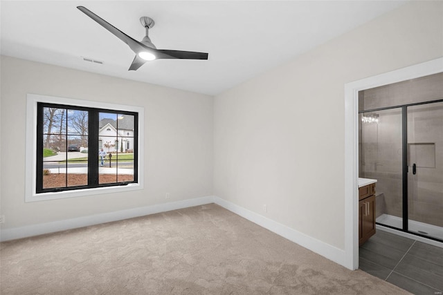 unfurnished bedroom featuring carpet floors, ceiling fan, and ensuite bath