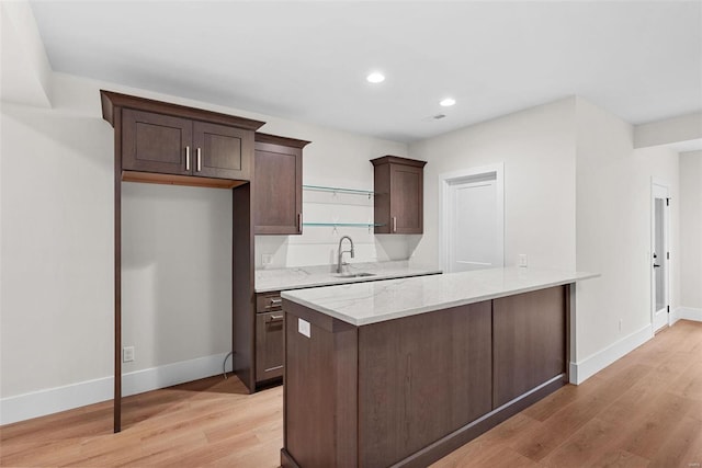 kitchen with light stone countertops, sink, light hardwood / wood-style floors, and dark brown cabinets