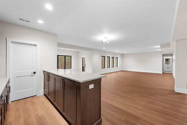 kitchen featuring light stone countertops, dark brown cabinetry, and light hardwood / wood-style flooring