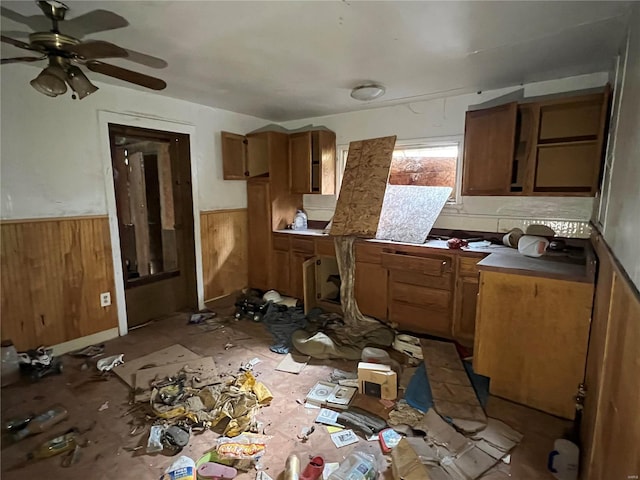 kitchen featuring ceiling fan and wood walls