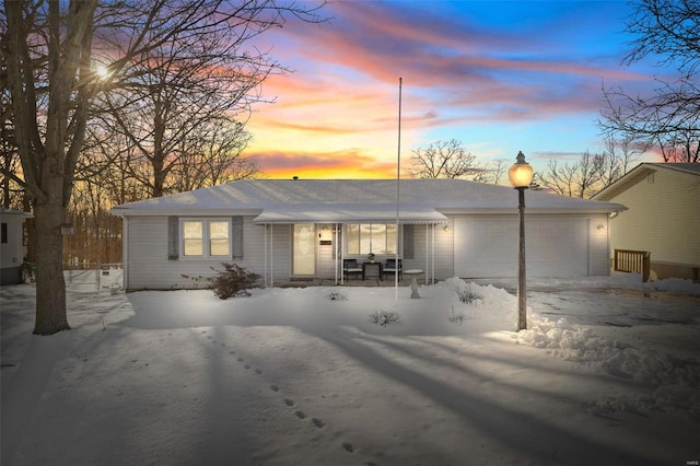 snow covered back of property featuring a garage