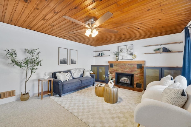 carpeted living room with a brick fireplace, ceiling fan, crown molding, and wood ceiling