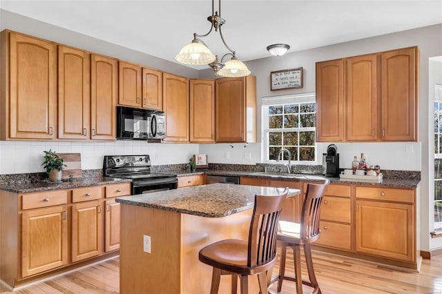 kitchen with black appliances, a center island, light wood-type flooring, and pendant lighting