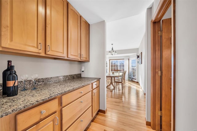 kitchen with light stone countertops, a chandelier, and light hardwood / wood-style floors