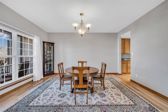 dining area with light hardwood / wood-style flooring and a chandelier