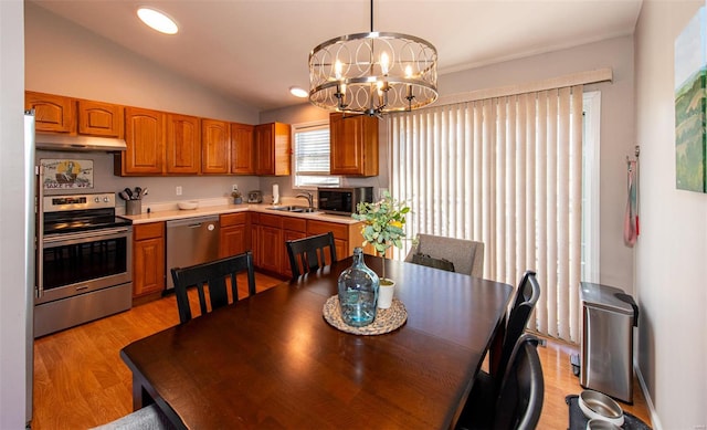 dining space with a chandelier, light hardwood / wood-style floors, sink, and vaulted ceiling