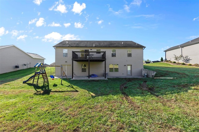 rear view of property featuring a playground, a lawn, a patio, and a deck