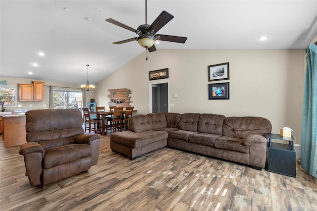 living room featuring hardwood / wood-style flooring, ceiling fan with notable chandelier, and vaulted ceiling