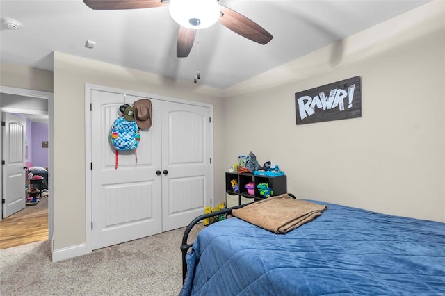 carpeted bedroom featuring ceiling fan and a closet