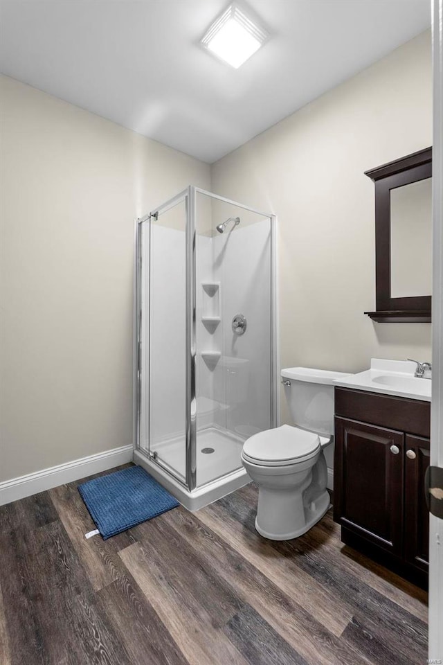 bathroom with wood-type flooring, vanity, toilet, and an enclosed shower