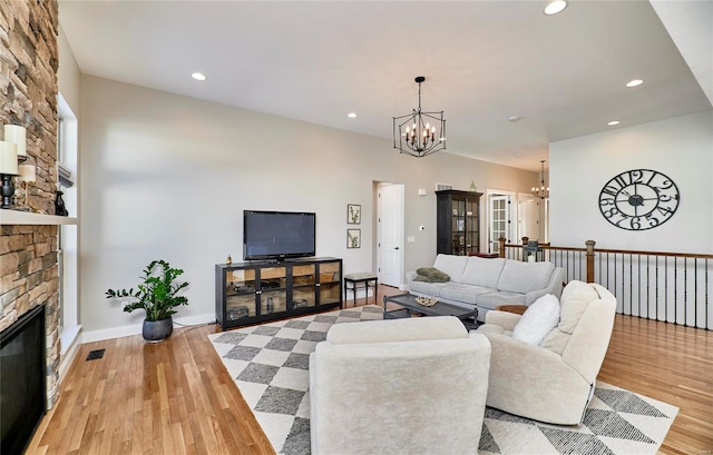 living room with a chandelier, a fireplace, and light hardwood / wood-style flooring