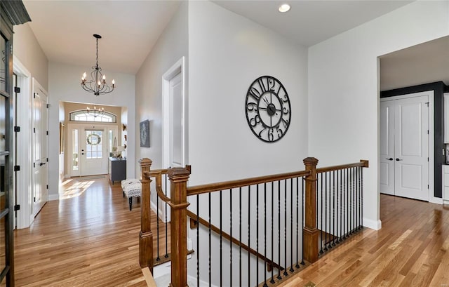 hall with light wood-type flooring and an inviting chandelier