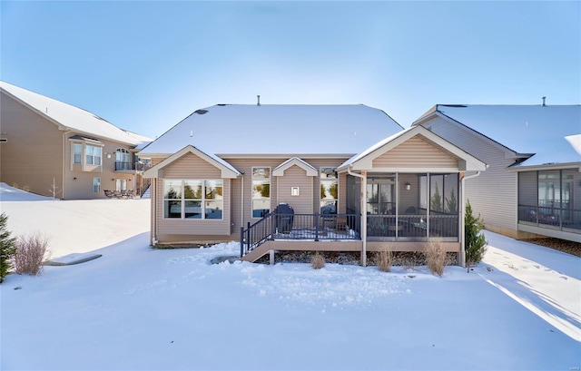 snow covered house featuring a sunroom and a deck