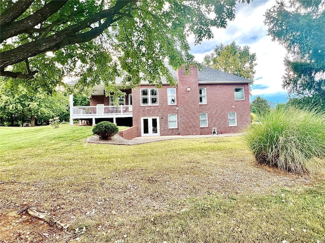 back of house featuring a lawn, a wooden deck, and french doors