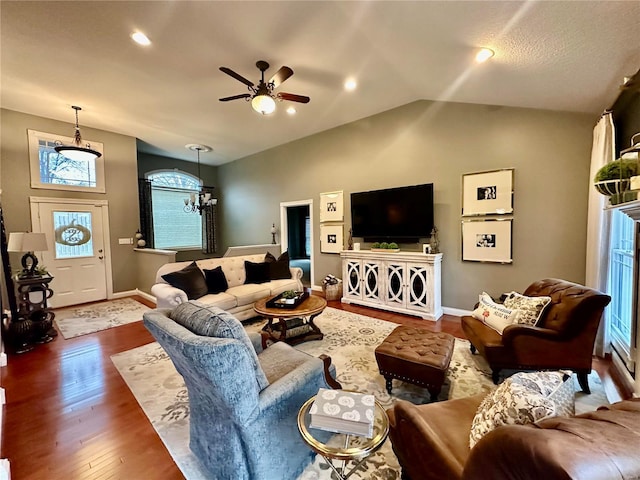 living room with hardwood / wood-style floors, ceiling fan with notable chandelier, and vaulted ceiling