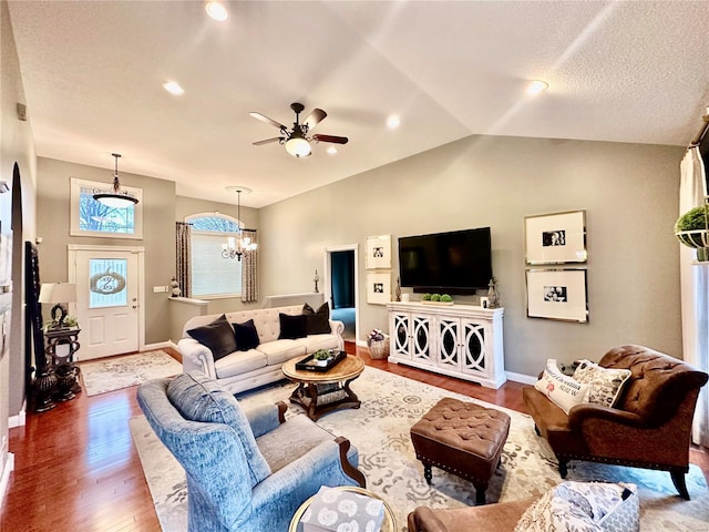 living room featuring wood-type flooring, ceiling fan with notable chandelier, and vaulted ceiling