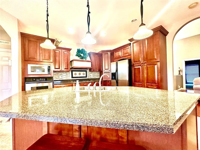 kitchen featuring light stone countertops, sink, hanging light fixtures, and appliances with stainless steel finishes