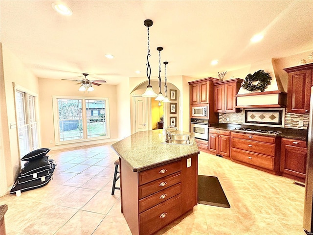 kitchen with sink, a kitchen breakfast bar, dark stone countertops, a kitchen island, and appliances with stainless steel finishes