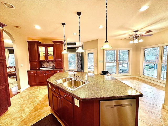 kitchen with a textured ceiling, sink, decorative light fixtures, dishwasher, and an island with sink