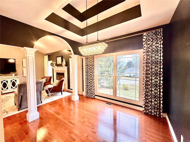 interior space featuring decorative columns, hardwood / wood-style floors, and a notable chandelier