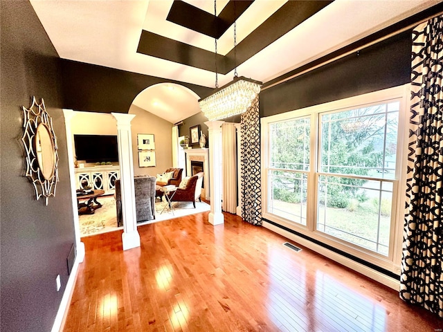 interior space with hardwood / wood-style floors, plenty of natural light, vaulted ceiling, and decorative columns