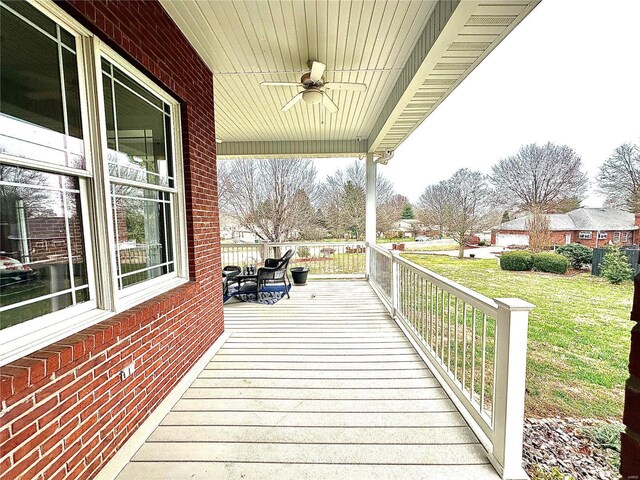 wooden terrace featuring a lawn, ceiling fan, and a porch